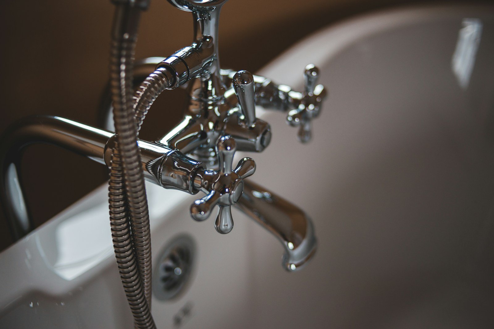 Chrome bathtub faucet and hand shower installed on a white tub